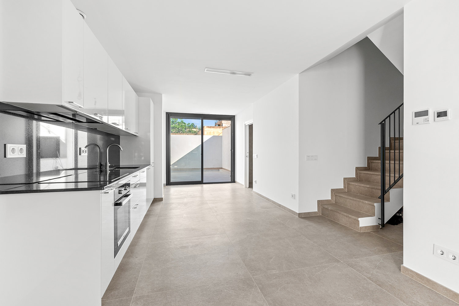 Salón-cocina abierto con escalera y acceso a terraza