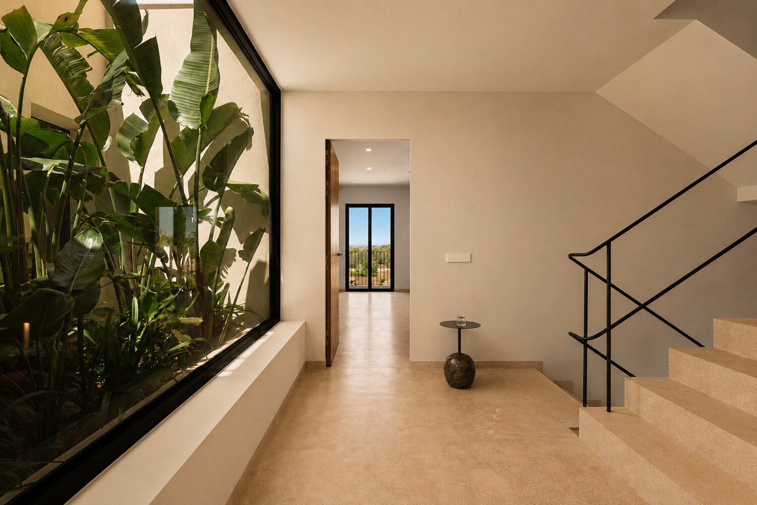Área de acceso elegante con escalera, barandilla metálica y patio interior con vegetación ornamental