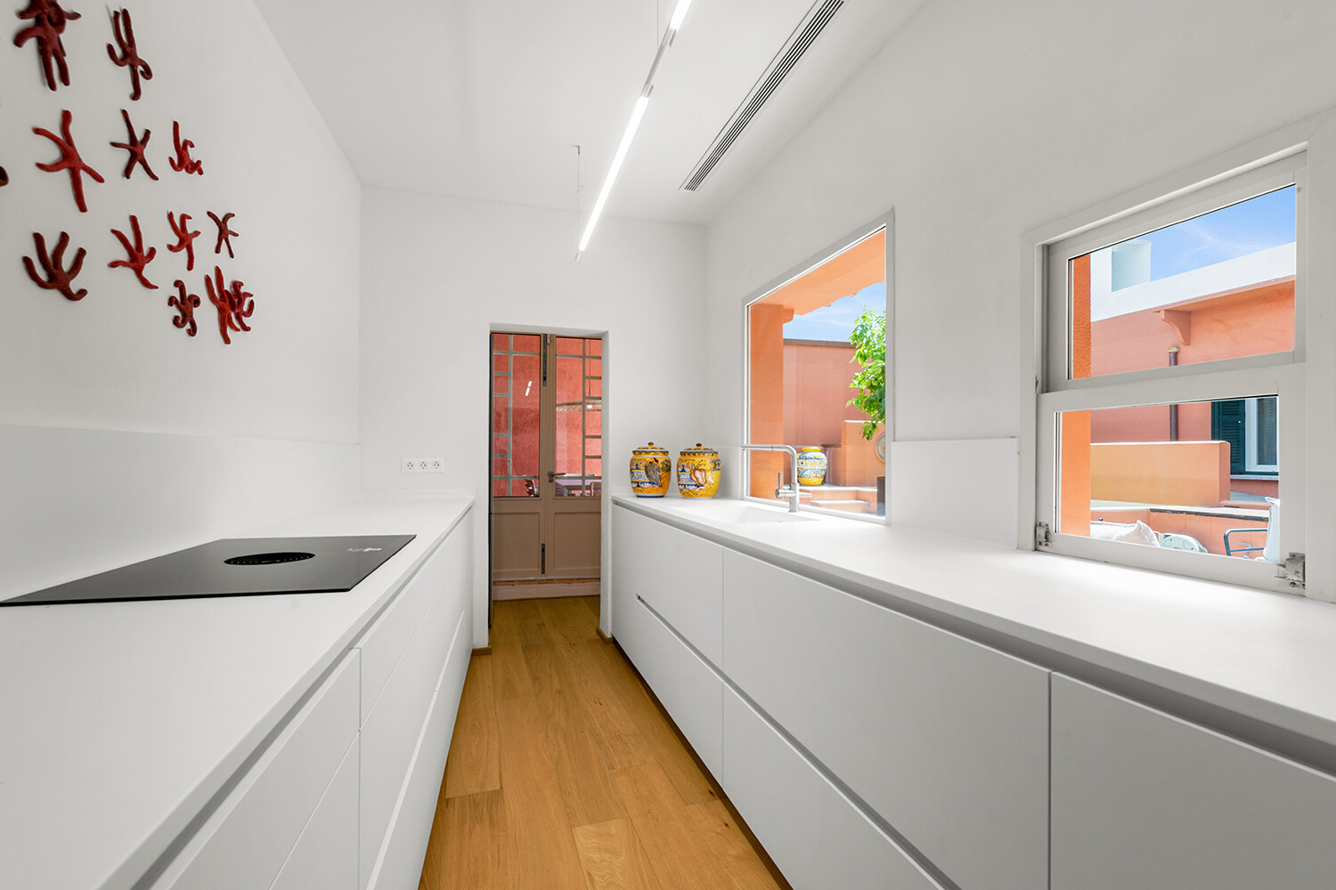 Cocina de diseño minimalista con mobiliario sin tiradores y conexión directa con el patio