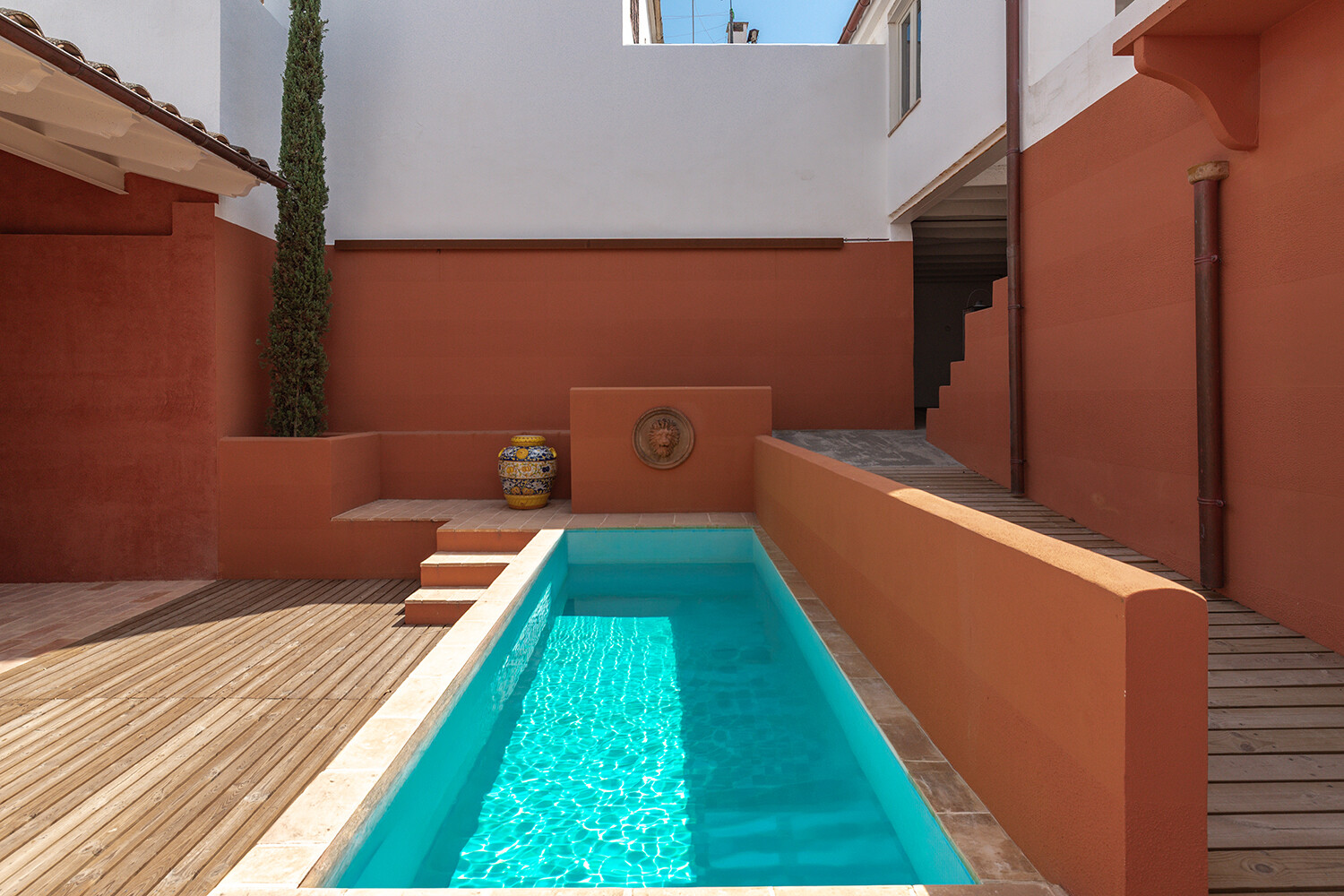 Patio privado con piscina alargada y tarima de madera perimetral